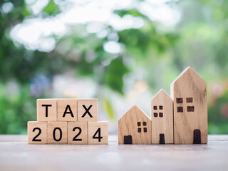 Wooden blocks with the word TAX 2024 and miniature house. The concept of Property investment, House...
