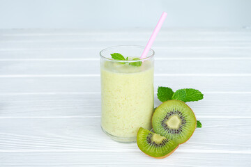 Kiwi yogurt fruit juice smoothie and green kiwi juice drink healthy, delicious taste in a glass for weight loss on a white wooden background.