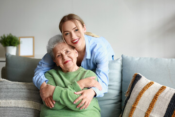 Young woman and her grandmother hugging at home - obrazy, fototapety, plakaty
