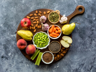 Various healthy fresh foods on a wooden board against a blue background.