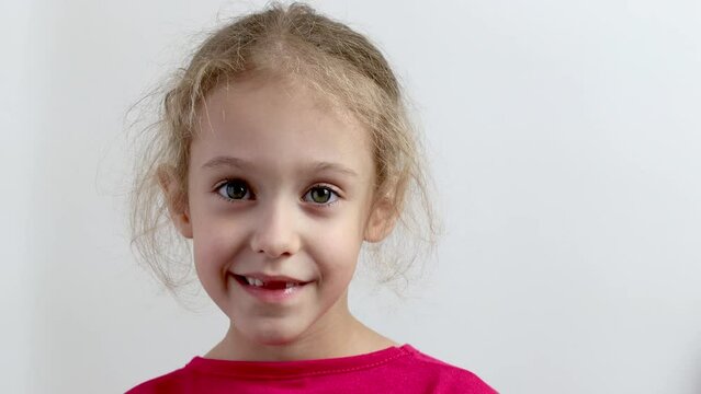 A little toothless girl smiles. Close-up. Isolated background