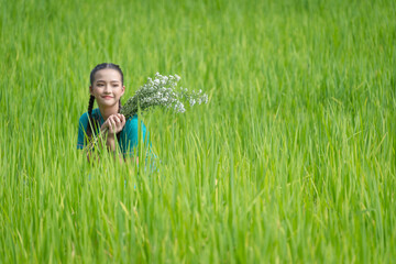 Naklejka na ściany i meble Pretty girl is happy in natural green organic Thai jasmine rice paddy crop on a plantation field growing during the growing season agriculture farming.