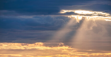 Sun rays shining through the overcast cloudy sky before rain in evening time, beautiful dramatic cloudscape sky background
