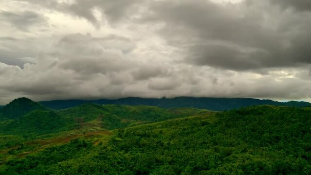 Cinematic aerial time lapse over the mountain landscapes of Mabini, Surigao Del Norte, Philippines. Fast moving clouds and lush jungle below.