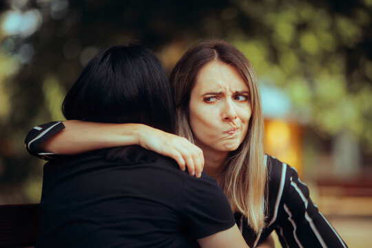 Woman Hugs Fake Friend Making Faces Behind her Back. Backstabbing toxic girlfriend embracing someone with bad intentions 
