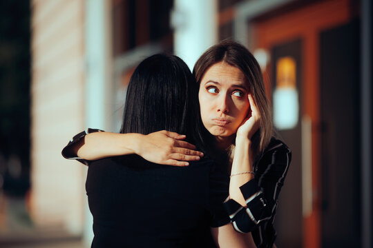 Woman Hugs Fake Friend Making Faces Behind her Back. Backstabbing toxic girlfriend embracing someone with bad intentions 
