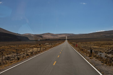A view through the bus window of a road through the highlands of Peru