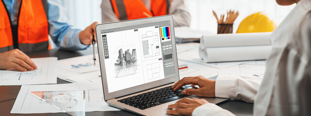 Engineer and architect working together brainstorming and designing blueprint using laptop working...