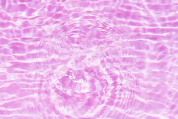 Purple water with ripples on the surface. Defocus blurred transparent pink colored clear calm water surface texture with splashes and bubbles. Water waves with shining pattern texture background.