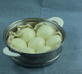 The image is of a bean paste bun sitting in a steamer basket. Bean paste buns that look like steamed buns on the outside but are filled with red bean paste on the inside. 