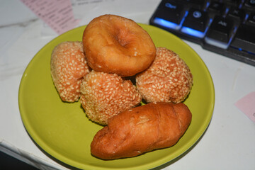 Donuts and dumplings on a small plate on a white background.