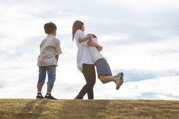 
丘の上で戯れ合う親子　Parent and child holding hands
