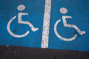 Des pictogrammes  representant un dessin d'une personne handicapée dans un fauteuil roulant sur fond bleu pour indiquer des places de parking réservées. - obrazy, fototapety, plakaty