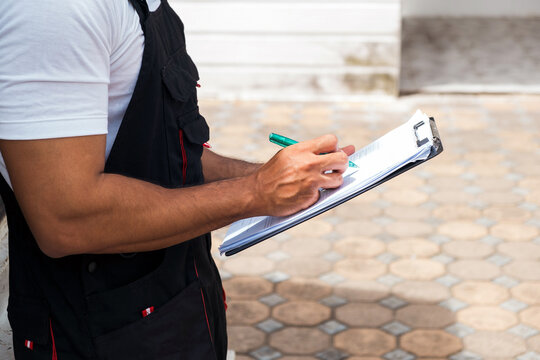 Crop image of truck driver holding a clipboard, checking the delivery packages checklists or paperwork and standing with a truck. Shipping cargo service, freight truck and transport logistics.