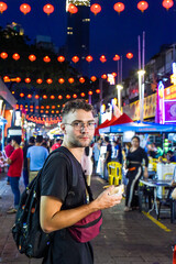 Fototapeta premium Young man tourist eating ice cream in Jalan Alor street food in Kuala Lumpur, Malaysia