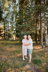 Fototapeta premium An elderly couple in love walks in the park and hugs each other. Love through the years