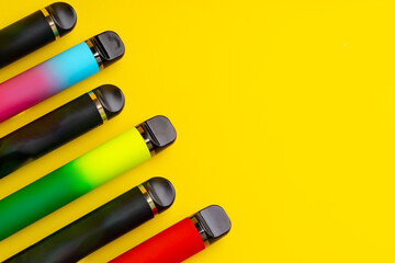 Colorful disposable electronic cigarettes on yellow background