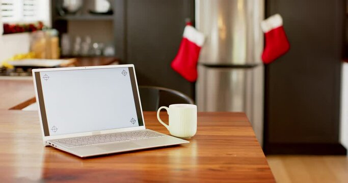 Laptop with blank screen on kitchen countertop at christmas, slow motion, copy space