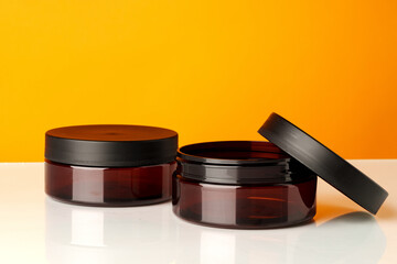 Round plastic cosmetic containers against orange background
