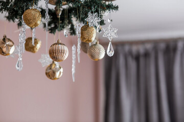 Stylish gold and crystal-clear toys on the Christmas tree. Beige tones. The concept of interior decoration and stylish new year and Christmas 2024.