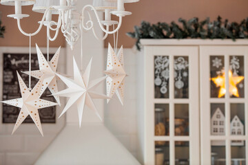 White Scandinavian paper stars in the Christmas decoration of the kitchen interior. The concept of...