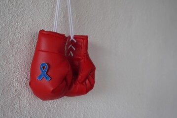 Close up image of boxing gloves and blue ribbon with copy space. Men's health, cancer awareness, stand against child abuse concept