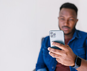 handsome dark-skinned african american guy with mobile phone on light background, social media concept