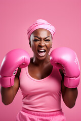 breast cancer awareness month: black woman in pink sports clothes punching with pink boxer gloves
