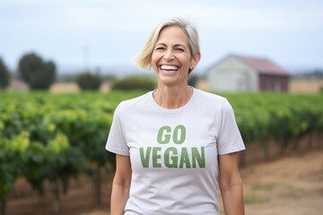 Woman vegan activist happily  while standing at vegetable farm. - obrazy, fototapety, plakaty