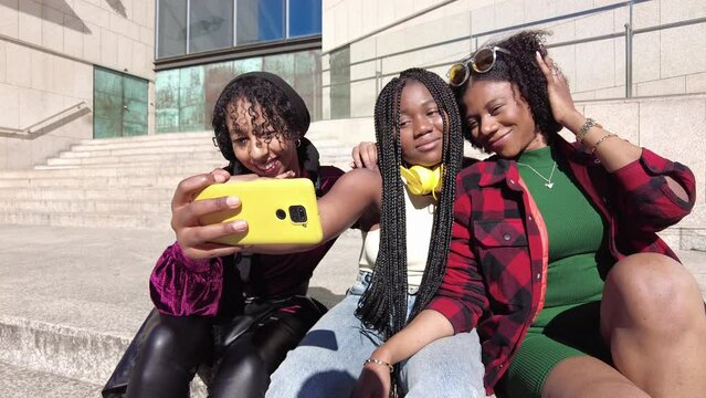Low angle view of three multi-ethnic friends smiling while sharing a mobile outdoors