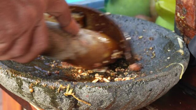 A footage of peanut sauce is being made in traditional way. Dressing of Indonesian fruit salad called rujak