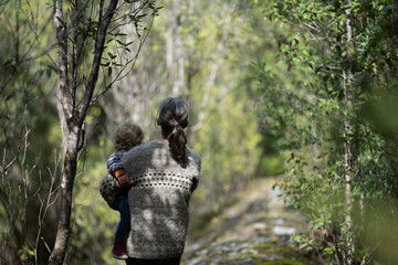 Mother with baby in a carrier on her chest on a hike, taking a bush walk in Summer in a national...