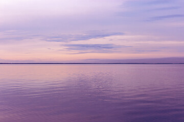 Colorful sky background on sunset or sunrise, purple pastel color clouds and surface water on lake...