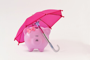 Piggy bank with hair bow under pink umbrella - Concept of woman, savings protection and financial security