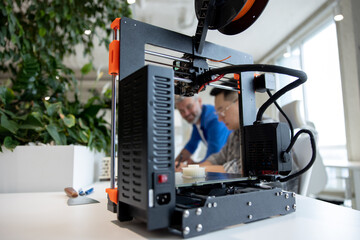 Two men architects using 3D printer in office and projecting house, drawing blueprints.