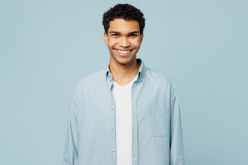 Young smiling cheerful satisfied fun cool man of African American ethnicity wearing shirt white t-shirt casual clothes look camera isolated on plain pastel light blue cyan background studio portrait.