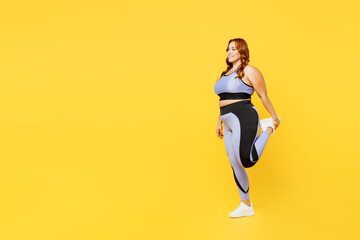 Fototapeta na wymiar Full body side view young chubby plus size big fat fit woman wear blue top warm up training raise up leg do stretch exercises isolated on plain yellow background studio home gym orkout sport concept