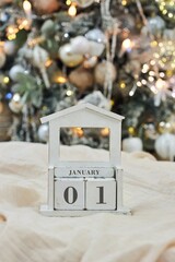 Vintage vintage calendar made of wood on the background of a Christmas tree. On the calendar, January 1, the first day of the new year
