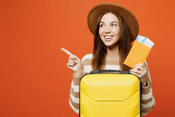 Traveler woman wears brown sweater hat hold bag passport ticket point aside isolated on plain...