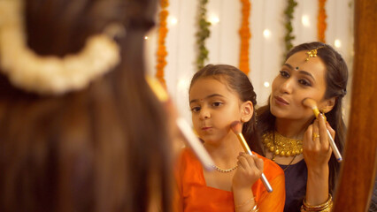 South Indian woman in traditional wear helping her daughter to get ready for the celebration of...