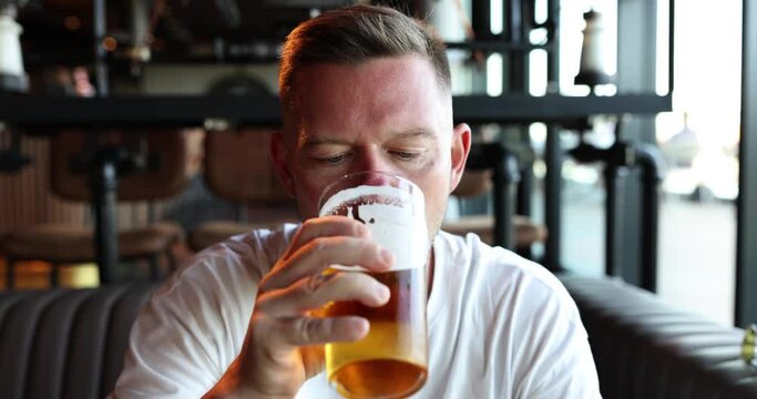 Portrait of handsome young man drinking delicious golden refreshing beer drink in pub. Man enjoying cold drink