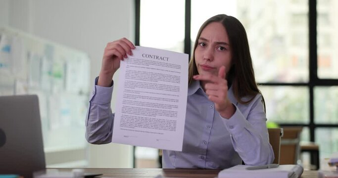 Businesswoman holds contract in hand, pointing with hand at contract documents. SEO manager demonstrates rules written in agreement document and signing