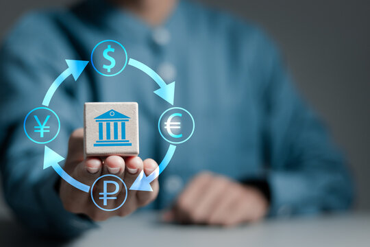 Foreign currency exchange digital concept. Businessman holds wooden cube with currency symbols of dollar, euro, ruble and yen. International money transfer or payments via online banking by fintech.