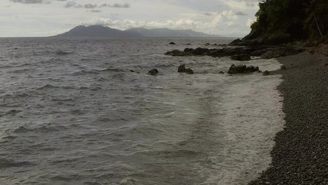 Ocean waves crash spread whitewash foam on pebble looc beach, perfect serenity