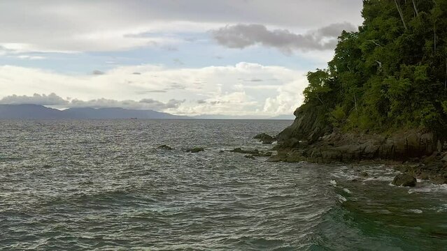 Scenic coastline of Looc beach surigao aerial dolly as tranquil ocean waves crash on coast