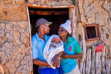 african family, father holding the baby , Botswana village, backyard view, at sunset
