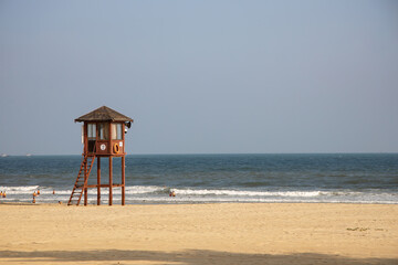 lifeguard tower on a hot sunny sandy beach with swimmers in the sea on Hainan Island China with...