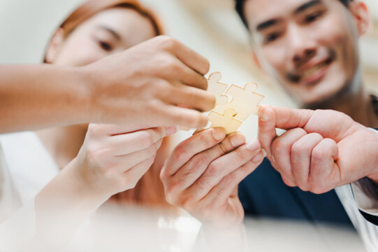 Closeup image of a group of people holding and putting a piece of white jigsaw puzzle together,A business group wishing to bring together the puzzle pieces