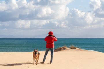 A person standing on a beach with a dog. With Copy space