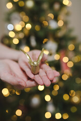 Hands that decorate the Christmas tree. Happy new year. Christmas card banner with decorative toy bird, bokeh lights. Mockup.